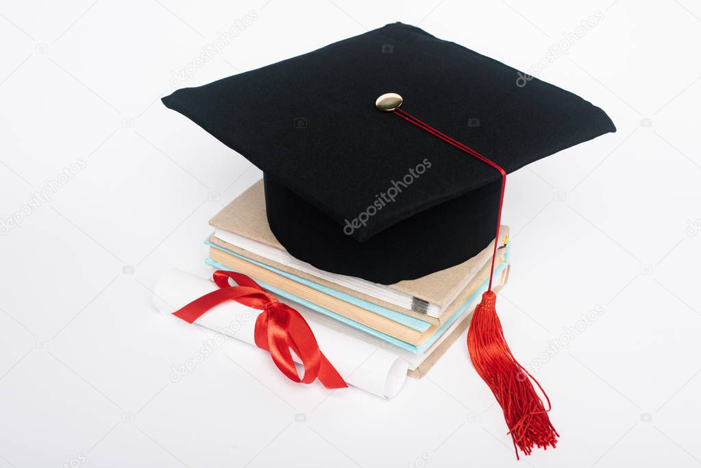 Black graduation cap with red tassel on top of books and diploma with bow isolated on white