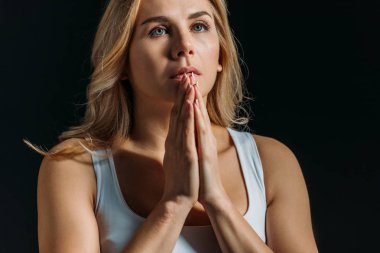 Woman with clenched hands praying isolated on black clipart