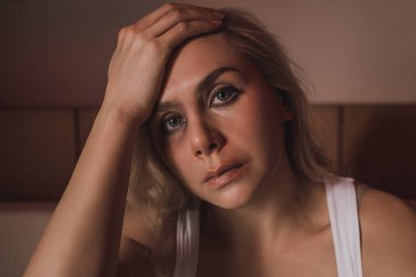 Yüzünde morluk olan mağdur kameraya bakıyor ve elini başına koyuyor. 