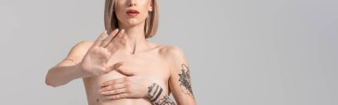 Gri, panoramik çekimlerde izole bir hareket göstermeyen seksi, üstsüz, dövmeli bir kadın görüntüsü.