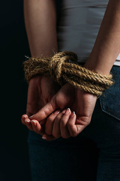 Partial view of female hands tied with rope isolated on black
