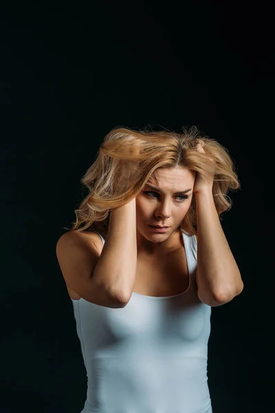 Frustrated woman holding head isolated on black