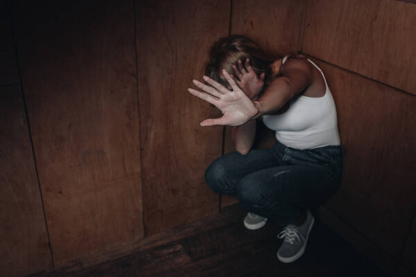 Victim with obscure face showing stop and hiding in corner 