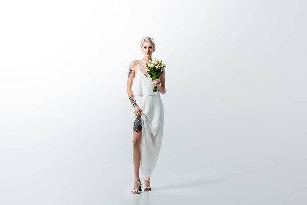beautiful tattooed bride with bouquet on white