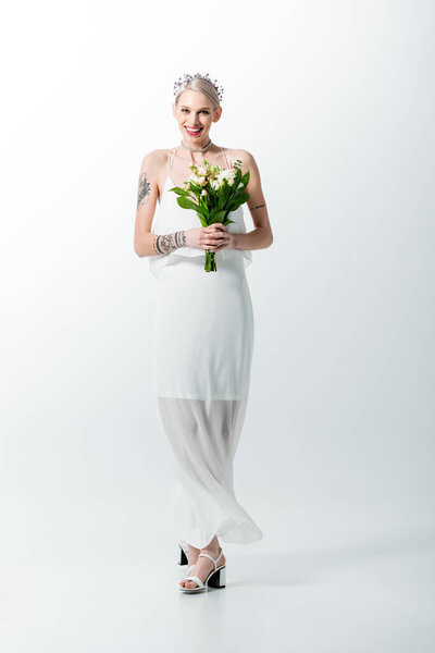 happy beautiful tattooed bride with bouquet on white