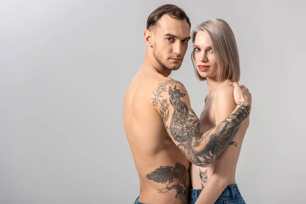 Zijaanzicht Van Jong Shirtloos Getatoeëerd Paar Jeans Knuffelen Geïsoleerd Grijs — Stockfoto