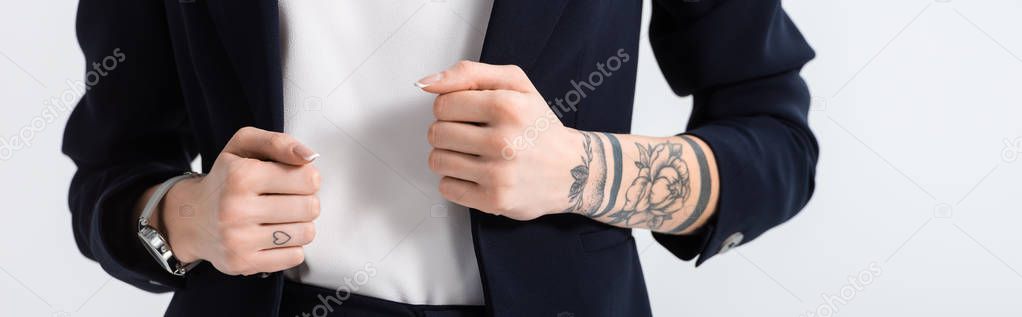 cropped view of successful young tattooed businesswoman with hands on blazer isolated on white, panoramic shot