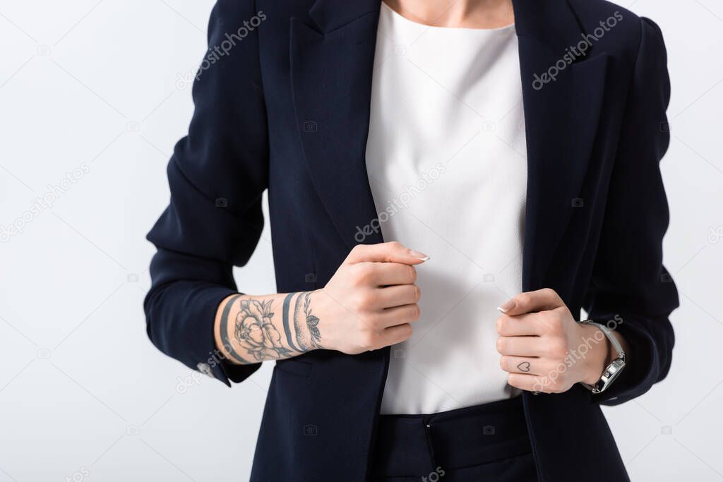 cropped view of successful young tattooed businesswoman with hands on blazer isolated on white