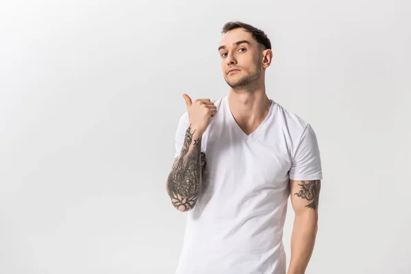 Pohledný Mladý Tetovaný Muž Ukazuje Prstem Stranou Izolované Bílém — Stock fotografie
