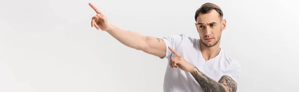Pohledný Mladý Tetovaný Muž Ukazuje Prsty Stranou Izolované Bílém Panoramatický — Stock fotografie