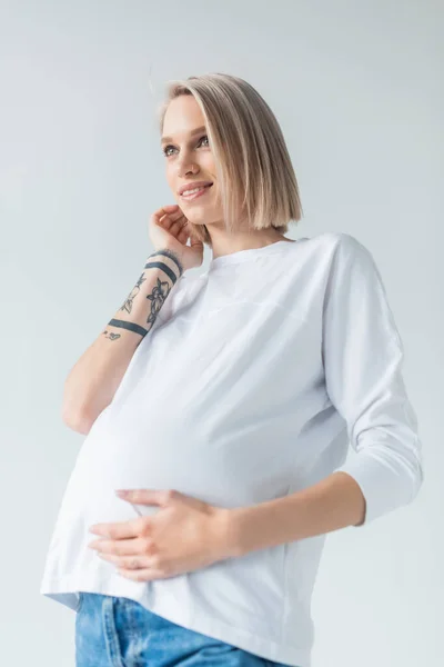 Usmívající Mladá Tetovaná Těhotná Žena Dotýkající Břicha Izolované Šedé — Stock fotografie