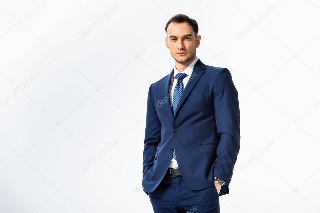 successful young businessman in blue suit with hands in pockets isolated on white