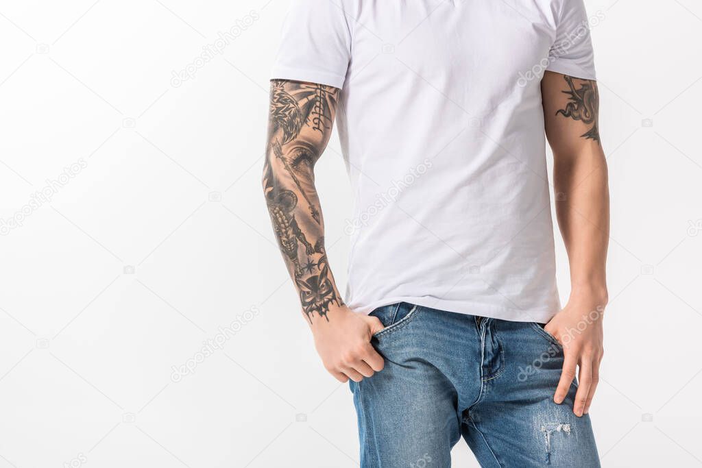 cropped view of young tattooed man in jeans posing isolated on white