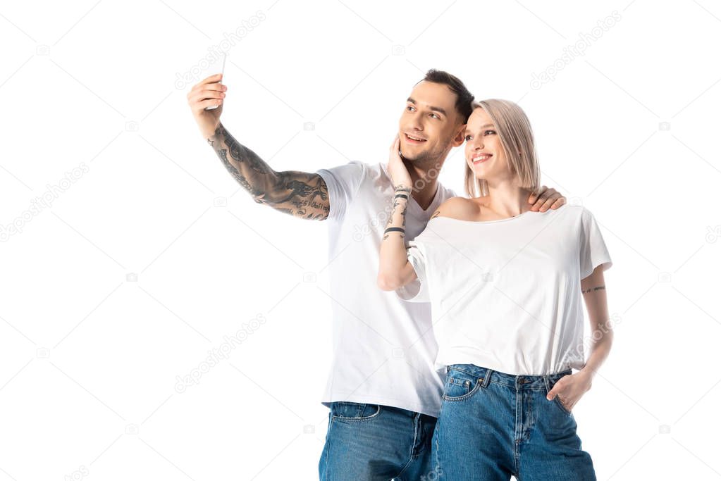 happy young tattooed couple taking selfie isolated on white