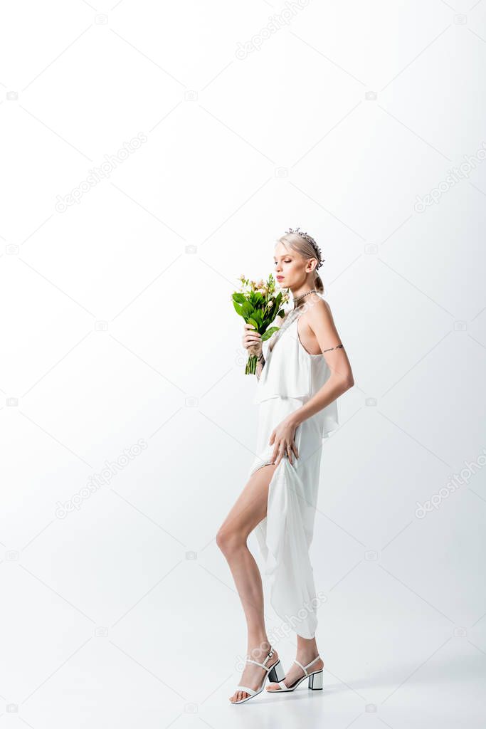 beautiful tattooed bride with floral bouquet on white