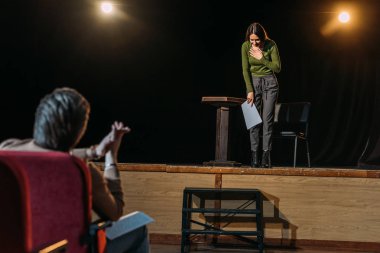 selective focus of theater director and bowing actress on stage clipart