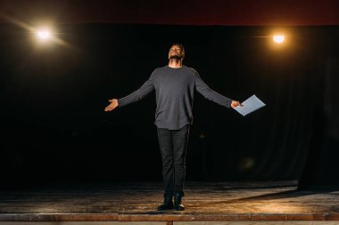 african american actor holding scenario and standing on stage during rehearse  clipart