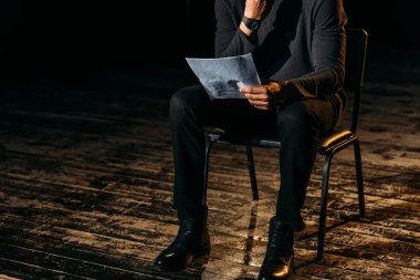 cropped view of african american actor holding scenario on stage during rehearse  clipart