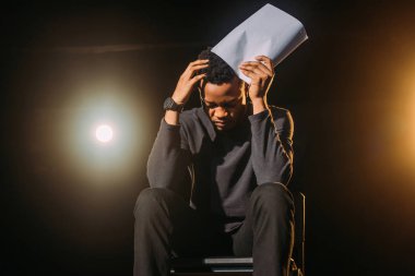 stressed african american actor holding scenario on stage during rehearse  clipart