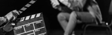 panoramic shot of actor with clapperboard in front, isolated on black, black and white clipart