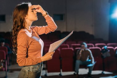 selective focus of theater director and attractive actress with screenplay on stage clipart