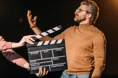 selective focus of mature actor performing role with clapboard in front  clipart
