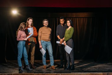 young multiethnic actors and actresses rehearsing with mature theater director on stage clipart