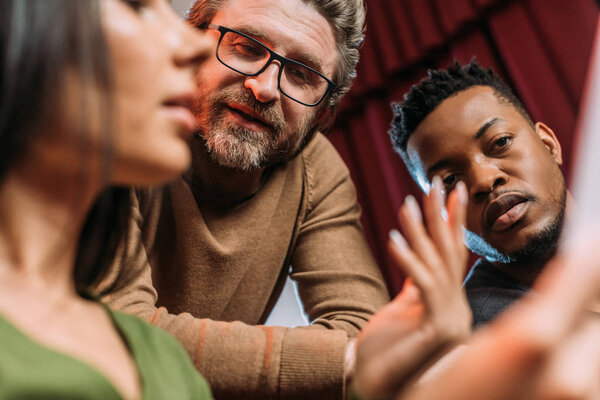 многокультурный актер и актриса, читающая сценарий со зрелым театральным режиссером
