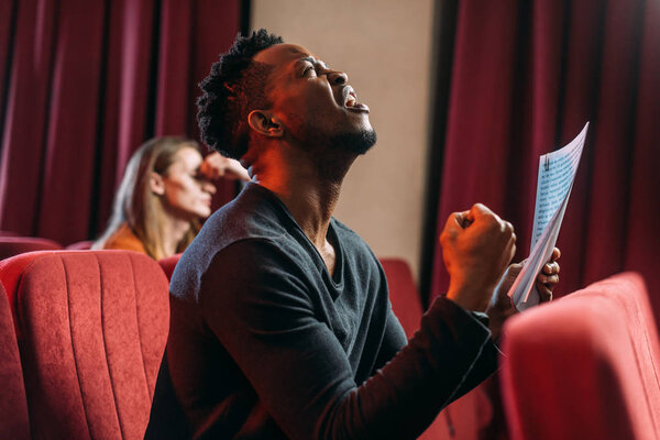 Африканский американский грустный актер кричит и репетирует в театре с молодым актером
