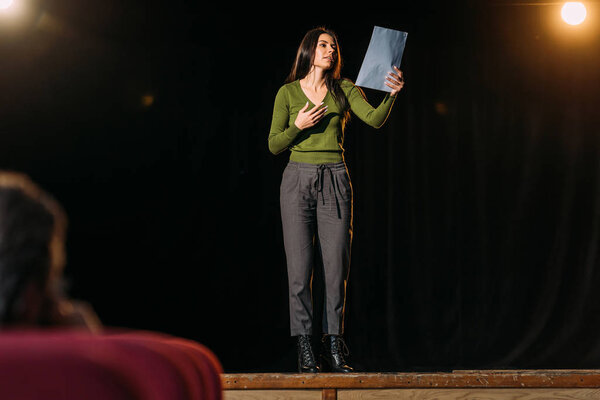 selective focus of theater director and attractive actress reading screenplay on stage