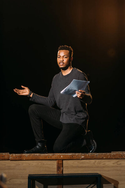 african american actor holding scenario on stage during rehearse 