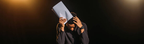 panoramic shot of emotional african american actor holding scenario on stage during rehearse 