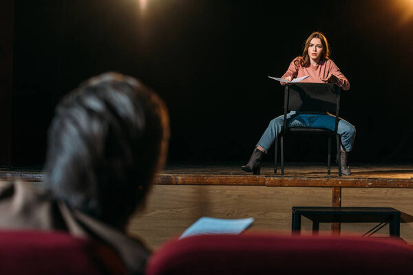 selective focus of stage director and actress performing role with screenplay in theater