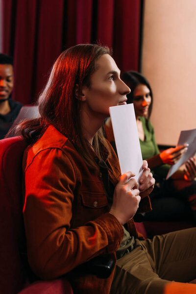 молодые мультиэтнические актеры и актрисы, читающие сценарии в театре
