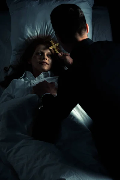 침대에서 여성의 소름끼치는 십자가를 엑소시스트 — 스톡 사진