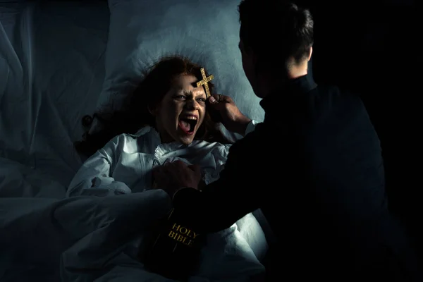 Exorcista Con Biblia Cruz Pie Sobre Demoniaca Gritando Chica Cama — Foto de Stock