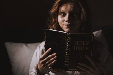 creepy demoniacal girl in nightgown holding holy bible  clipart