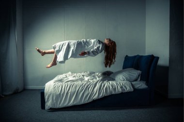 demonic girl in nightgown levitating over bed clipart