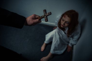 exorcist holding cross in front of obsessed girl clipart