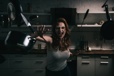 Şeytani bağıran kız mutfaktaki mutfak eşyalarıyla el kol hareketi yapıyor.