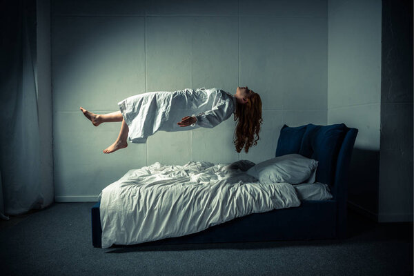 демоническая девушка в ночной рубашке левитирует над кроватью
