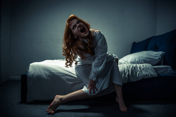 Демоническая жуткая девушка в ночной рубашке кричит в спальне
