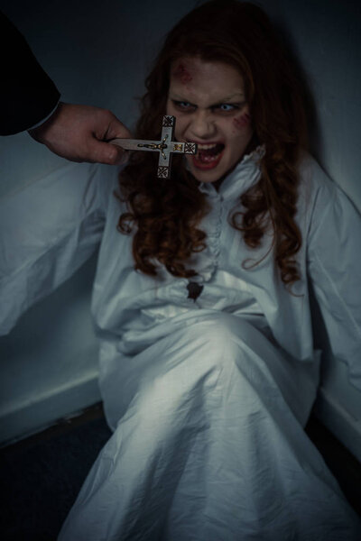 exorcist holding cross in front of yelling female demon