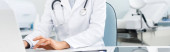 Panoramaaufnahme einer Ärztin bei der Arbeit am Laptop in der Klinik  