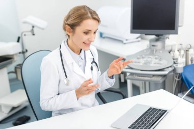 Klinikte laptopta ultrason tarayıcısıyla çalışan profesyonel bir kadın doktor.