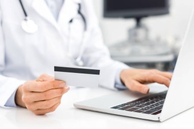 Klinikte bilgisayar ve kredi kartı kullanan doktor görüşü