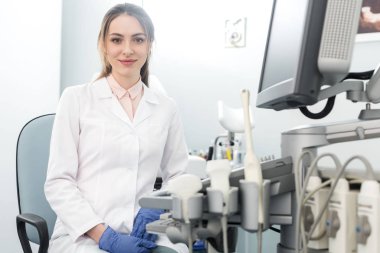 Genç, güzel doktor klinikte ultrason tarayıcısıyla çalışıyor.