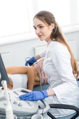 Genç profesyonel doktor ultrason taramasıyla kadın hastanın böbreğini inceliyor. 