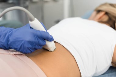 Kadın hastanın ultrason taramasıyla böbreğini inceleyen doktorun kısmi görüntüsü.