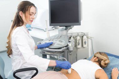 Genç bayan doktor, klinikte ultrason taraması yapılan hastanın böbreğini inceliyor.  
